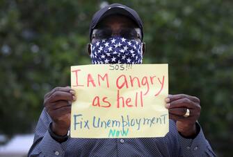 (FILES) In this file photo taken on May 22, 2020, Odirus Charles holds a sign that reads, ' I Am angry as hell Fix Unemployment Now,' as he joins others in a protest in Miami Beach, Florida. - Another 2.12 million people filed for unemployment in the US last week, pushing total layoffs since the start of the coronavirus crisis to more than 40 million, a level not seen since the Great Depression, the Labor Department said on May 28, 2020. The new filings, however, showed that the pace of the layoffs was subsiding as the US economy slowly begins to reopen. (Photo by JOE RAEDLE / GETTY IMAGES NORTH AMERICA / AFP)