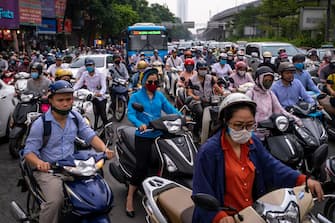 HANOI, VIETNAM - MAY 19: Motorbike riders with face masks are stuck in traffic during the morning peak hour on May 19, 2020 in Hanoi, Vietnam. Though some restrictions remain in place, Vietnam has lifted the ban on certain entertainment facilities and non-essential businesses, including pubs, cinemas and spas & other tourist attractions to recover domestic tourism. On April 23, the Ministry of Transport started to increase domestic flights and trains to major destinations with limited passenger capacity. As of May 19, Vietnam has confirmed 324 cases of coronavirus disease (COVID-19 ) with no deaths in the country, 263 fully recovered and no new case caused by community transmission for 33 days. (Photo by Linh Pham/Getty Images)