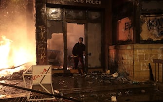 MINNEAPOLIS, MINNESOTA - MAY 28: A protester walks out of the Minneapolis 3rd Precinct police building as it burns on May 28, 2020 in Minneapolis, Minnesota. Today marks the third day of ongoing protests after the police killing of George Floyd. Four Minneapolis police officers were fired after a video taken by a bystander was posted on social media showing Floyd's neck being pinned to the ground by an officer as he repeatedly said, "I can’t breathe." Floyd was later pronounced dead while in police custody after being transported to Hennepin County Medical Center. (Photo by Scott Olson/Getty Images)