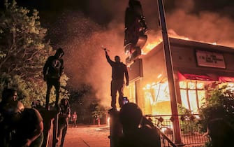 epa08451206 Protesters burn an Arby's fast food restaurant near the Minneapolis Police Department 3rd Precinct during protests over the arrest of George Floyd, who later died in police custody, in Minneapolis, Minnesota, USA, 28 May 2020. A bystander's video posted online on 25 May, appeared to show George Floyd, 46, pleading with arresting officers that he couldn't breathe as an officer knelt on his neck. The unarmed black man later died in police custody.  EPA/TANNEN MAURY