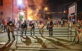 Protesters push a shopping cart corral from a Target store into the street near the Third Police Precinct on May 28, 2020 in Minneapolis, Minnesota, during a protest over the death of George Floyd, an unarmed black man, who died after a police officer kneeled on his neck for several minutes. - A police precinct in Minnesota went up in flames late on May 28 in a third day of demonstrations as the so-called Twin Cities of Minneapolis and St. Paul seethed over the shocking police killing of a handcuffed black man. The precinct, which police had abandoned, burned after a group of protesters pushed through barriers around the building, breaking windows and chanting slogans. A much larger crowd demonstrated as the building went up in flames. (Photo by Kerem Yucel / AFP) (Photo by KEREM YUCEL/AFP via Getty Images)