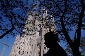 A woman walks in front of the Sagrada Familia in Barcelona on April 10, 2020, during a national lockdown to prevent the spread of the COVID-19 disease. - Spain has recorded its lowest daily death toll from the new coronavirus in 17 days, with 605 people dying, the government said. (Photo by Pau Barrena / AFP) (Photo by PAU BARRENA/AFP via Getty Images)