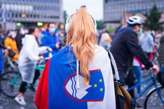 A woman wears a Slovenian flag as protesters, some wearing face masks, stand with their bicycles outside the Slovenian National Assembly building and block the centre the capital Ljubljana, on May 15, 2020, during a demonstration to protest against the centre-right government, accusing it of corruption and of using the COVID-19 (the novel coronavirus) crisis to restrict freedom. (Photo by Jure Makovec / AFP) (Photo by JURE MAKOVEC/AFP via Getty Images)