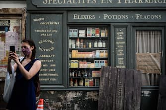 TOPSHOT - A woman takes a picture in front of a cinema set as work resume prior to filming in a street of the Montmartre hill touristic neighbourhood of Paris on May 26, 2020 after the filming was halted amid the crisis caused by the Covid-19 pandemic (novel coronavirus) (Photo by Philippe Lopez / AFP) (Photo by PHILIPPE LOPEZ/AFP via Getty Images)