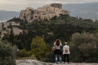 People visit the Pnyx Hill in Athens overlooking the ancient Acropolis on May 29, 2020 as Greece eases lockdown measures taken to curb the spread of the COVID-19 (the novel coronavirus). - Greece announced a list of 29 countries deemed to fit the epidemiological profile , allowed to fly to Greece from 15 June as the country opens for tourists. (Photo by Louisa GOULIAMAKI / AFP) (Photo by LOUISA GOULIAMAKI/AFP via Getty Images)