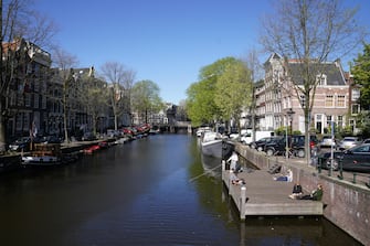 AMSTERDAM, NETHERLANDS, APRIL 20: People enjoy the sun on a wooden deck at a deserted Brouwersgracht amid the coronavirus outbreak on April 20, 2020 in Amsterdam, Netherlands. The city is unusually quiet due to the worldwide coronavirus (COVID-19) pandemic, which causes tourists to stay away. (Photo by Henk Seppen/BSR Agency/Getty Images)