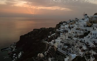 The sun sets over the village of Oia, on the northwestern tip of the Greek island of Santorini, in the Aegean Sea on May 20, 2020. - The government on May 20, 2020, said the  tourism period would begin on June 15 with the first resumption of international flights through Athens  airport. Direct flights to the Greek islands will begin July 1. (Photo by Dimitris LAMBROPOULOS / AFP) (Photo by DIMITRIS LAMBROPOULOS/AFP via Getty Images)