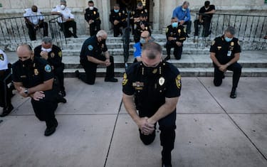 TOPSHOT - Police officers kneel during a rally in Coral Gables, Florida on May 30, 2020 in response to the recent death of George Floyd, an unarmed black man who died while being arrested and pinned to the ground by a Minneapolis police officer. - Clashes broke out and major cities imposed curfews as America began another night of unrest Saturday with angry demonstrators ignoring warnings from President Donald Trump that his government would stop violent protests over police brutality "cold." (Photo by Eva Marie UZCATEGUI / AFP)