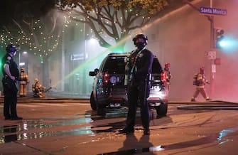 SANTA MONICA, CALIFORNIA - MAY 31:  Police stand guard as firefighters work to extinguish a fire at a section of shops looted amid demonstrations in the aftermath of George Floydâ  s death on May 31, 2020 in Santa Monica, California. California Governor Gavin Newsom has deployed National Guard troops to Los Angeles County to curb the looting and destruction of property. Former Minneapolis police officer Derek Chauvin was taken into custody for Floyd's death. Chauvin has been accused of kneeling on Floyd's neck as he pleaded with him about not being able to breathe. Floyd was pronounced dead a short while later. Chauvin and 3 other officers, who were involved in the arrest, were fired from the police department after a video of the arrest was circulated. (Photo by Mario Tama/Getty Images)