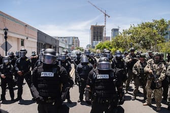 San Diego Police officers (L) in riot gear and a special tactics group (R) face-off with demonstrators in downtown San Diego, California on May 31, 2020, as people gather to protest against the death of Minneapolis man George Floyd. - Numerous cities across the US saw another day of violent protests after Floyd, an African-American, died on May 25 after being handcuffed and as a white police officer, who has since been charged with murder, knelt on his neck. (Photo by ARIANA DREHSLER / AFP) (Photo by ARIANA DREHSLER/AFP via Getty Images)