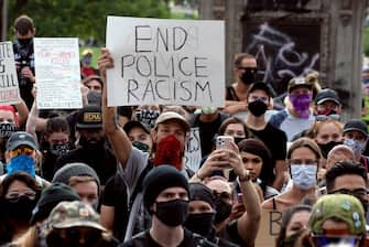 A demonstrator holds up a sign during a protest in Denver, Colorado on May 31, 2020, while protesting the death of George Floyd, an unarmed black man who died while while being arrested and pinned to the ground by the knee of a Minneapolis police officer. - Thousands of National Guard troops patrolled major US cities  after five consecutive nights of protests over racism and police brutality that boiled over into arson and looting, sending shock waves through the country. The death Monday of an unarmed black man, George Floyd, at the hands of police in Minneapolis ignited this latest wave of outrage in the US over law enforcement's repeated use of lethal force against African Americans -- this one like others before captured on cellphone video. (Photo by Jason Connolly / AFP) (Photo by JASON CONNOLLY/AFP via Getty Images)