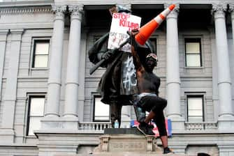 A demonstrator stands on a Civil War statue in Denver, Colorado on May 31, 2020, while protesting the death of George Floyd, an unarmed black man who died while while being arrested and pinned to the ground by the knee of a Minneapolis police officer. - Thousands of National Guard troops patrolled major US cities  after five consecutive nights of protests over racism and police brutality that boiled over into arson and looting, sending shock waves through the country. The death Monday of an unarmed black man, George Floyd, at the hands of police in Minneapolis ignited this latest wave of outrage in the US over law enforcement's repeated use of lethal force against African Americans -- this one like others before captured on cellphone video. (Photo by Jason Connolly / AFP) (Photo by JASON CONNOLLY/AFP via Getty Images)