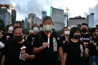 Chairman of the Alliance in Support of Patriotic Democratic Movements of China and former Legislative Council member, Lee Cheuk-yan (C), leads a candlelit remembrance with other activists after crossing downed barricades into Victoria Park in Hong Kong on June 4, 2020, after the annual vigil that traditionally takes place in the park to mark the 1989 Tiananmen Square crackdown was banned on public health grounds because of the COVID-19 coronavirus pandemic. (Photo by Anthony WALLACE / AFP) (Photo by ANTHONY WALLACE/AFP via Getty Images)