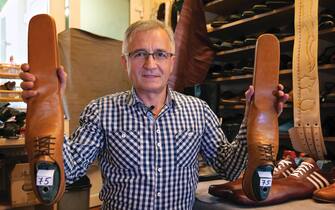 ROMANIA FASHION PANDEMIC COVID19 CORONAVIRUS epa08466342 Romanian shoemaker Grigore Lup displays a pair of men's social-distancing shoes he invented during the Coronavirus pandemic, at his workshop, in Cluj Napoca city, 500 kms north-west of Bucharest, Romania, 04 June 2020 (issued 05 June 2020). Lup, 55, invented the social distancing shoes in a bid to save his small business in the midst of the Coronavirus crisis. The shoemaker is manufacturing by hand each pair of social distancing shoes, measuring 75 centimeters, using the best natural leather, hand tools plus his 39 years professional experience. After receiving attention from the local media, he began to receive orders from around the world. Most of his customers are confessing that they want to wear his creations on the street or at special occasions. The master shoemaker, who managed to survive the global financial crisis of 2008 by moving from normal shoes to the production of footwear for dance companies and theaters, turned the disadvantage of the Covid-19 pandemic in his favor, producing social distance shoes for both men and women. He is selling a pair of his special shoes for about 100 euros. EPA/Alexandru Pop To go with the story: 'Number 75 shoes to enforce social distance' by Marcel Gascon/EFE