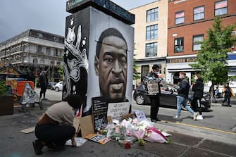 Protesters place their placards at the base of a mural of George Floyd, by street artist Akse, following a demonstration in Manchester, northern England, on June 6, 2020, to show solidarity with the Black Lives Matter movement in the wake of the killing of George Floyd, an unarmed black man who died after a police officer knelt on his neck in Minneapolis. - The United States braced Friday for massive weekend protests against racism and police brutality, as outrage soared over the latest law enforcement abuses against demonstrators that were caught on camera. With protests over last week's police killing of George Floyd, an unarmed black man, surging into a second weekend, President Donald Trump sparked fresh controversy by saying it was a "great day" for Floyd. (Photo by Paul ELLIS / AFP) / RESTRICTED TO EDITORIAL USE - MANDATORY MENTION OF THE ARTIST UPON PUBLICATION - TO ILLUSTRATE THE EVENT AS SPECIFIED IN THE CAPTION