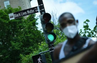 A woman is seen in front of a street sign for the newly proclaimed "Black Lives Matter Plaza" near the White House in Washington, DC, on June 5 2020. (Photo by MANDEL NGAN / AFP) (Photo by MANDEL NGAN/AFP via Getty Images)