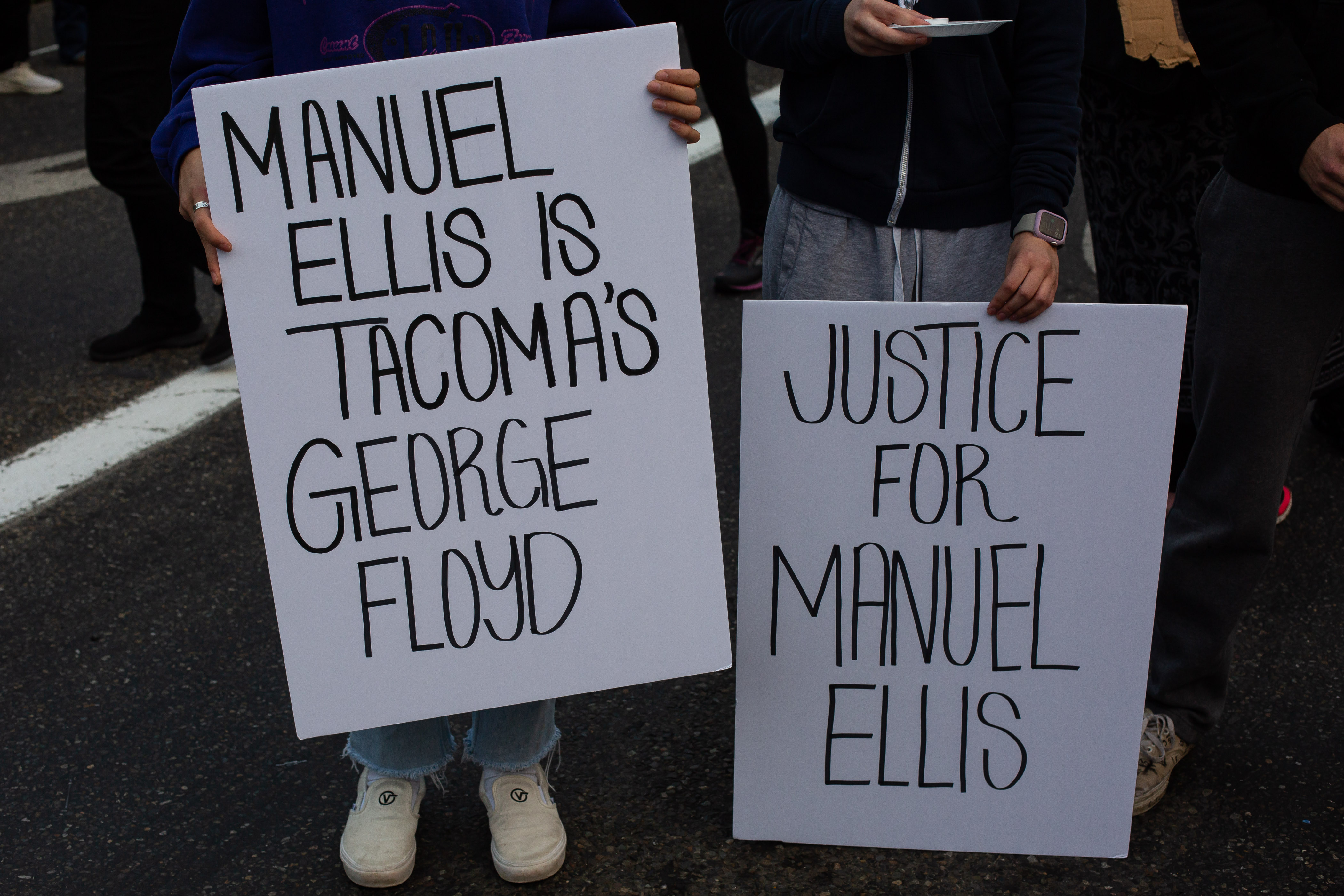 TACOMA, WA - JUNE 03: People hold signs during a vigil for Manuel Ellis, a black man whose March death while in Tacoma Police custody was recently found to be a homicide, according to the Pierce County Medical Examiners Office, near the site of his death on June 3, 2020 in Tacoma, Washington. Protests and other events sparked by the death of George Floyd have continued in the Tacoma area after the Medical Examiner found that the cause of death in the Manuel Ellis case was caused by respiratory arrest due to hypoxia due to physical restraint. (Photo by David Ryder/Getty Images)