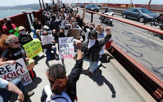 epa08470521 Black Lives Matter protest organizer Tiana Day (C) has protesters take a knee to remember George Floyd during a march across the Golden Gate Bridge to protest police brutality, in San Francisco, California, USA, 06 June 2020.  EPA/JOHN G. MABANGLO