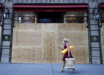 A woman walks by a boarded up Cartier store on 5th Avenue in New York City June 8, 2020. - Today New York City enters "Phase 1" of a four-part reopening plan after spending more than two months under lockdown. New York City is the final region in the state to reopen its economy. (Photo by TIMOTHY A. CLARY / AFP) (Photo by TIMOTHY A. CLARY/AFP via Getty Images)