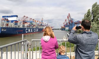 HAMBURG, GERMANY - JUNE 07: People watch as the HMM Algeciras, currently the world's largest container ship, arrives on its maiden voyage on June 07, 2020 in Hamburg, Germany. The ship is 399.9 meters long and 61 meters wide, and has a nominal capacity to transport 23,964 containers. It is the first in a series of twelve ships in the 24,000 TEU class and was built in South Korea. (Photo by Stuart Franklin/Getty Images)