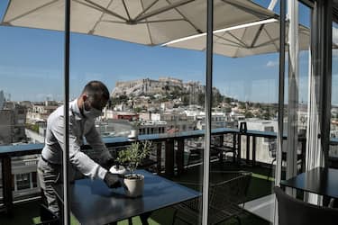 A waiter prepares tables in a roof cafe of an hotel central Athens on June 1, 2020, as Greece eases coronavirus measures and reopening some of the hotels , priomary schools and nurseries. - Greece on May 30, 2020 expanded its list of approved flights from EU destinations to include airports in countries hard-hit by the coronavirus, but flights from the worst-hit regions will still be subject to quarantine measures. (Photo by Louisa GOULIAMAKI / AFP) (Photo by LOUISA GOULIAMAKI/AFP via Getty Images)