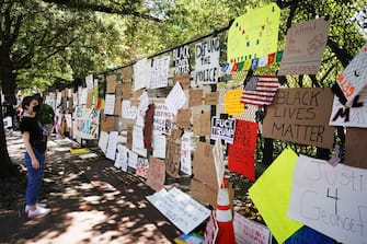 1218644272 A woman looks at messages attached to the security fence on the north side of Lafayette Square, near the White House, in Washington, DC on June 8, 2020. - On May 25, 2020, Floyd, a 46-year-old black man suspected of passing a counterfeit $20 bill, died in Minneapolis after Derek Chauvin, a white police officer, pressed his knee to Floyd's neck for almost nine minutes. (Photo by MANDEL NGAN / AFP) (Photo by MANDEL NGAN/AFP via Getty Images)