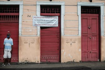 RIO DE JANEIRO, BRAZIL - JUNE 09: A man wearing a face mask stands in front of a shuttered and closed traditional bar in the Santa Teresa neighborhood with a banner that reads in Portuguese "Don't let us close the doors. We need immediate support from banks and the government. #DontLetTheTabClose" amidst the coronavirus (COVID-19) pandemic on June 9, 2020 in Rio de Janeiro, Brazil. Many businesses in the city of Rio de Janeiro went bankrupt and some commercial spaces are either for sale or for lease during the coronavirus (COVID-19) pandemic. (Photo by Bruna Prado/Getty Images)