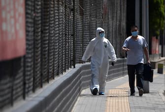 TOPSHOT - A man wearing a protective suit walks near the Guangan Sport Center where swab tests for people that live or visited Xinfadi market is taking place in Beijing on June 15, 2020. - China locks down ten more Beijing neighbourhoods over virus cluster. (Photo by Noel Celis / AFP) (Photo by NOEL CELIS/AFP via Getty Images)