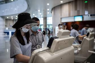 This photo taken on June 14, 2020 shows residents wearing face masks checking information on a self-service machine at Hubei Libruary as it reopens to the public in Wuhan in China's central Hubei province. (Photo by STR / AFP) / China OUT (Photo by STR/AFP via Getty Images)