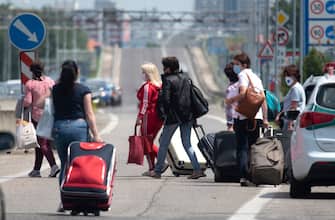 Women walk with their luggage while crossing the Bratislava-Berg border crossing between Austria and Slovakia during the coronavirus COVID-19 pandemic on June 4, 2020. - Austria has re-opened its borders to all its neighbors except Italy, although the neighboring countries did not reciprocate reopening of frontier crossings, testing the patience of some motorists and other travelers. (Photo by JOE KLAMAR / AFP) (Photo by JOE KLAMAR/AFP via Getty Images)