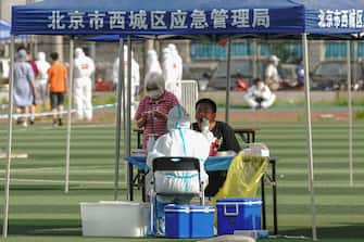 BEIJING, CHINA - JUNE 15:  A Chinese nurse wearing a protective suit takes a nucleic acid test from a man at Guangan Sport Center for citizens who visited or live near the Xinfadi Market on June 14, 2020 in Beijing, China. From June 11 to June 14, Beijing reported a total of 79 new confirmed cases of new coronary pneumonia (covid-19), the number of new infection has risen after no new cases for nearly two months.  (Photo by Lintao Zhang/Getty Images)