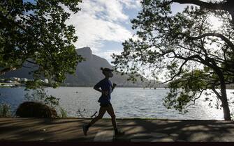 RIO DE JANEIRO, BRAZIL - JUNE 17: A woman wearing a face mask jogs by the Rodrigo de Freitas Lagoon amidst the coronavirus (COVID-19) pandemic on June 17, 2020 in Rio de Janeiro, Brazil. The city of Rio de Janeiro started today the second phase of the quarantine flexibilization. The decree determines the return of 100% of the bus fleet and some commercial establishments following distance rules such as reduced opening hours, restricting the flow of people and maintaining hygiene standards. (Photo by Andre Coelho/Getty Images)
