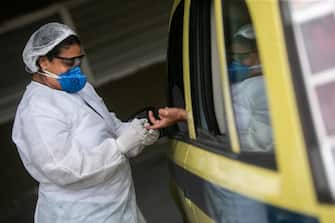 RIO DE JANEIRO, BRAZIL - JUNE 15: Health worker performs a test of coronavirus (COVID-19) to a taxi driver through a drive-thru system at the Marques de Sapucai Sambadrome on June 15, 2020 in Rio de Janeiro, Brazil. The municipality of Rio de Janeiro is testing taxi drivers with the most chance of exposing themselves to the virus, and the order will be defined according to the number of runs made through the TaxiRio (a taxi ride app from the city of Rio de Janeiro) application. With the drive-thru system, the taxi driver will not have the need to disembark from the vehicle to collect material, and the test result will be sent via a text message on the cell phone. The city expects to complete the testing of 5,000 taxi drivers in ten days. (Photo by Bruna Prado/Getty Images)