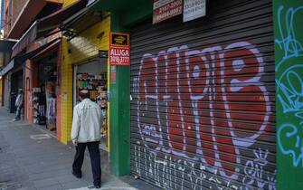 A man walks past an empty store to rent in a comercial area of Sao Paulo, Brazil, on June 17, 2020. - Sao Paulo is resuming its economic activity, but in some streets of Brazil's largest metropolis a succession of low iron curtains is evidence of the impact of the coronavirus: merchants have closed down. (Photo by NELSON ALMEIDA / AFP) (Photo by NELSON ALMEIDA/AFP via Getty Images)