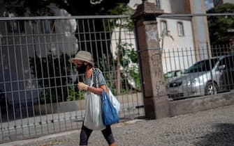 1220701803 A woman walks wearing a face mask amid concern to the COVID-19 pandemic coronavirus at the Lapa neighbourhood in Rio de Janeiro, Brazil, on June 17, 2020. (Photo by MAURO PIMENTEL / AFP) (Photo by MAURO PIMENTEL/AFP via Getty Images)