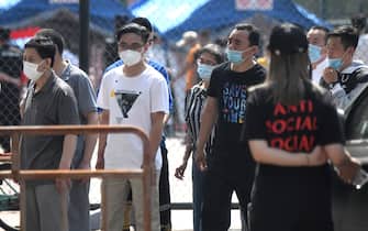 People wearing face masks wait to take a swab test for the COVID-19 coronavirus as officials conduct mass testing following a new cluster of cases last week, in Beijing on June 18, 2020. - Beijing reported another 21 cases of the coronavirus on June 18, as authorities rushed to contain a new outbreak in the capital and warned cases may keep rising. (Photo by Noel Celis / AFP) (Photo by NOEL CELIS/AFP via Getty Images)