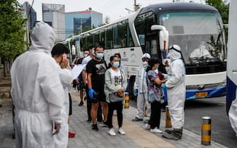 People who had their car number plates recorded in the area of the Xinfadi market where a new COVID-19 coronavirus cluster emerged last week, wait to do swab tests for the coronavirus after being transported with buses to a testing centre in Beijing on June 17, 2020. - China closed schools in Beijing and restricted air travel from the capital on June 17 to halt an outbreak of coronavirus cases and dampen fears of a second wave, as India's death toll spiked. (Photo by GREG BAKER / AFP) (Photo by GREG BAKER/AFP via Getty Images)
