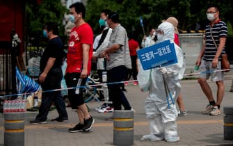 A member of the medical staff in full protective gear holds up a sign to assist people who live near or who have visited the Xinfadi Market, a wholesale food market where a new COVID-19 coronavirus cluster has emerged, as they arrive for testing in Beijing on June 17, 2020. - Beijing's airports cancelled two-thirds of all flights and schools in the Chinese capital were closed again on June 17 as authorities rushed to contain a new coronavirus outbreak linked to the Xinfadi wholesale food market. (Photo by NOEL CELIS / AFP) (Photo by NOEL CELIS/AFP via Getty Images)