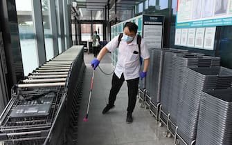 A worker disinfects shopping baskets and carts at the entrance of a supermarket in Beijing on June 17, 2020. - The supermarket has stepped up virus prevention work after a new outbreak of the COVID-19 coronavirus at a wholesale market in Beijing last week. (Photo by GREG BAKER / AFP) (Photo by GREG BAKER/AFP via Getty Images)