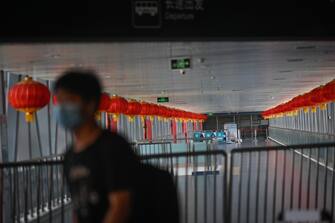 A man wearing a face mask walks past a long-distance bus terminal closed due to the COVID-19 coronavirus outbreak in Beijing on June 19, 2020. - Travel restrictions were placed on nearly half a million people near Beijing on June 18 as authorities rushed to contain a fresh outbreak of the coronavirus with a mass test-and-trace effort and lockdowns in parts of the Chinese capital. (Photo by WANG Zhao / AFP) (Photo by WANG ZHAO/AFP via Getty Images)