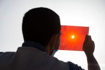 epa08499601 A man uses an X-ray plate to observe an annular partial solar eclipse in Cairo, Egypt, 21 June 2020. A partial solar eclipse occurs when a portion of the Earth is engulfed by the shadow (penumbra) cast by the Moon as it passes between our planet and the Sun in imperfect alignment. During this annular eclipse   the first of the decade   the Moon appears to cover the Sun, leaving the Sun's halo as a visible rim forming an annulus, popularly known as the 'ring of fire.'  EPA/MOHAMED HOSSAM