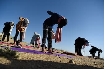 Women perform a yoga posture as they take part in a yoga session at Shahrak Haji Nabi hilltop during International Yoga Day, on the outskirts of Kabul on June 21, 2020. (Photo by WAKIL KOHSAR / AFP) (Photo by WAKIL KOHSAR/AFP via Getty Images)