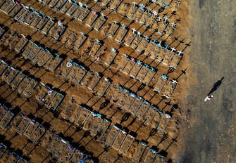 Aerial view showing a man walking past graves in the Nossa Senhora Aparecida cemetery in Manaus on June 21, 2020. - The novel coronavirus has killed at least 464,423 people worldwide since the outbreak began in China last December, being Brazil Latin America's worsthit country with 49,976 deaths from 1,067,579 cases. (Photo by MICHAEL DANTAS / AFP)