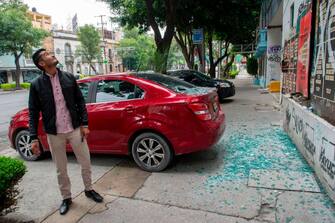A man looks at a building after his car was damaged by a broken glass and objects which fell over it during a quake in Mexico City, on June 23, 2020, amid the new coronavirus pandemic. - A 7.1 magnitude quake was registered Tuesday in the south of Mexico, according to the Mexican National Seismological Service. (Photo by CLAUDIO CRUZ / AFP) (Photo by CLAUDIO CRUZ/AFP via Getty Images)