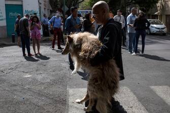 MEXICO CITY, MEXICO - JUNE 23: A man holds his dog to be safe as people stand in the street during an earthquake on June 23, 2020 in Mexico City, Mexico.  According to the National Seismological Service a 7.5 magnitude earthquake was registered on Tuesday in Mexico City and in various areas of the country. (Photo by Cristopher Rogel Blanquet/Getty Images)
