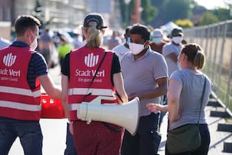 GUETERSLOH, GERMANY - JUNE 23: City employees give food and water to residents of apartment buildings that house workers from the nearby Toennies meat packing plant who are under quarantine in the town of Verl following a Covid-19 outbreak among Toennies workers during the coronavirus pandemic on June 23, 2020 near Guetersloh, Germany. State authorities announced today they are placing the entire Guetersloh region into semi-lockdown following confirmed Covid-19 infections among over 1,500 employees of the plant. The Bundeswehr, the German armed forces, has stepped in to help test people at the approximately 250 houses and apartment complexes where Toennies employees, many of whom come from Romania, Bulgaria and Poland, live throughout the Guetersloh region. (Photo by Sean Gallup/Getty Images)