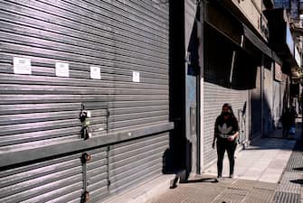 A woman walks past closed clothing stores in Buenos Aires, on June 18, 2020, amid the new coronavirus pandemic. - After two years of economic recession and three months of compulsory confinement due to the COVID-19 pandemic, several stores and restaurants in Buenos Aires are auctioning their furniture and implements, convinced they will not be able to reopen. (Photo by RONALDO SCHEMIDT / AFP) (Photo by RONALDO SCHEMIDT/AFP via Getty Images)