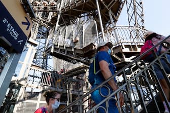 Visitors wearing protective facemasks walk up the stairs to the second floor as they visit the Eiffel Tower during its partial reopening on June 25, 2020, in Paris, as France eases lockdown measures taken to curb the spread of the COVID-19 caused by the novel coronavirus. - Tourists and Parisians will again be able to admire the view of the French capital from the Eiffel Tower after a three-month closure due to the coronavirus -- but only if they take the stairs. (Photo by Thomas SAMSON / AFP) (Photo by THOMAS SAMSON/AFP via Getty Images)