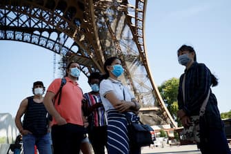 Visitors wearing protective facemasks queue as they wait for the partial reopening of Eiffel Tower on June 25, 2020, in Paris, as France eases lockdown measures taken to curb the spread of the COVID-19 caused by the novel coronavirus. - Tourists and Parisians will again be able to admire the view of the French capital from the Eiffel Tower after a three-month closure due to the coronavirus -- but only if they take the stairs. (Photo by Thomas SAMSON / AFP) (Photo by THOMAS SAMSON/AFP via Getty Images)