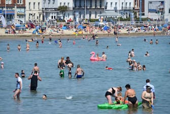 WEYMOUTH, ENGLAND - JUNE 24: Visitors enjoy the hot weather on the beach on June 24, 2020 in Weymouth, United Kingdom. The UK is experiencing a summer heatwave, with temperatures in many parts of the country expected to rise above 30C and weather warnings in place for thunderstorms at the end of the week. (Photo by Finnbarr Webster/Getty Images)